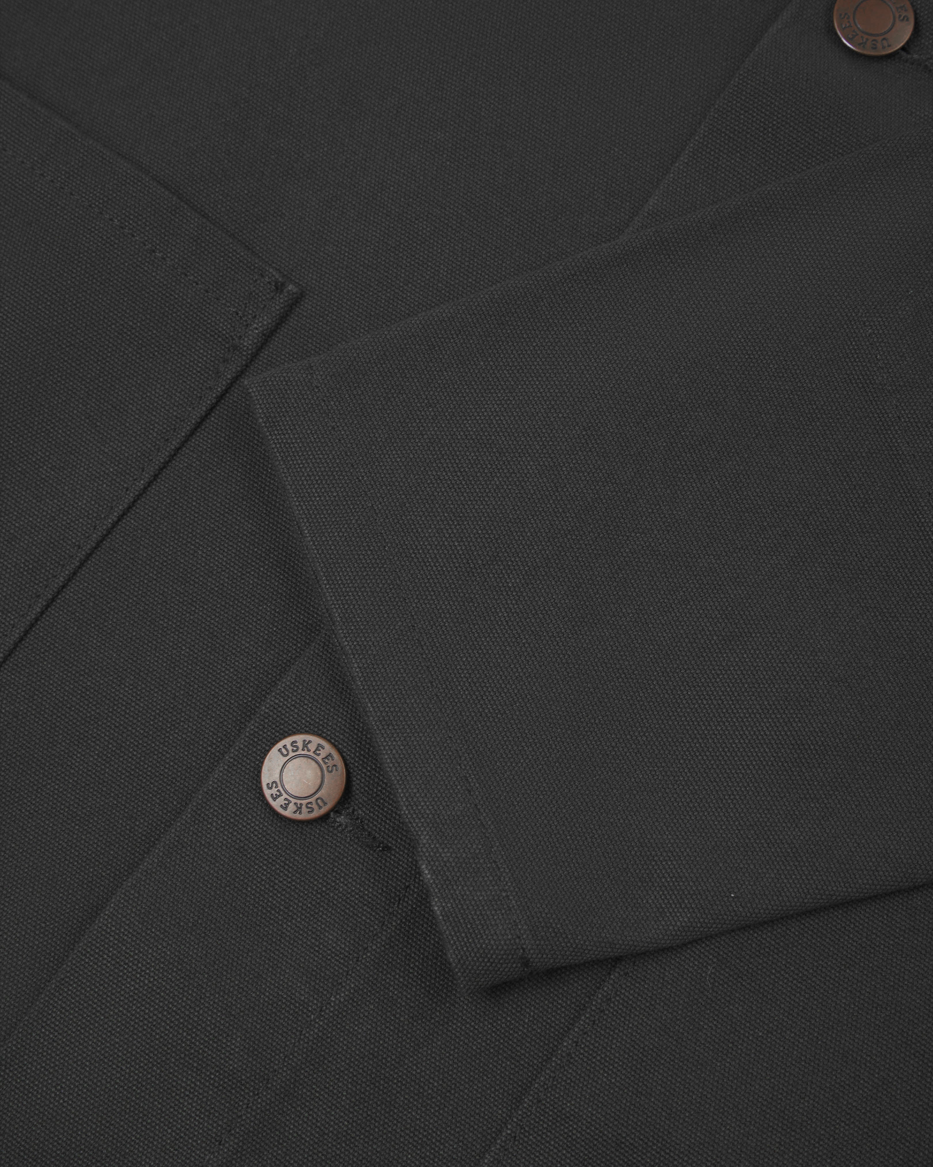 Close view of uskees dark grey canvas men's shacket showing the cuff/sleeve and metal buttons..