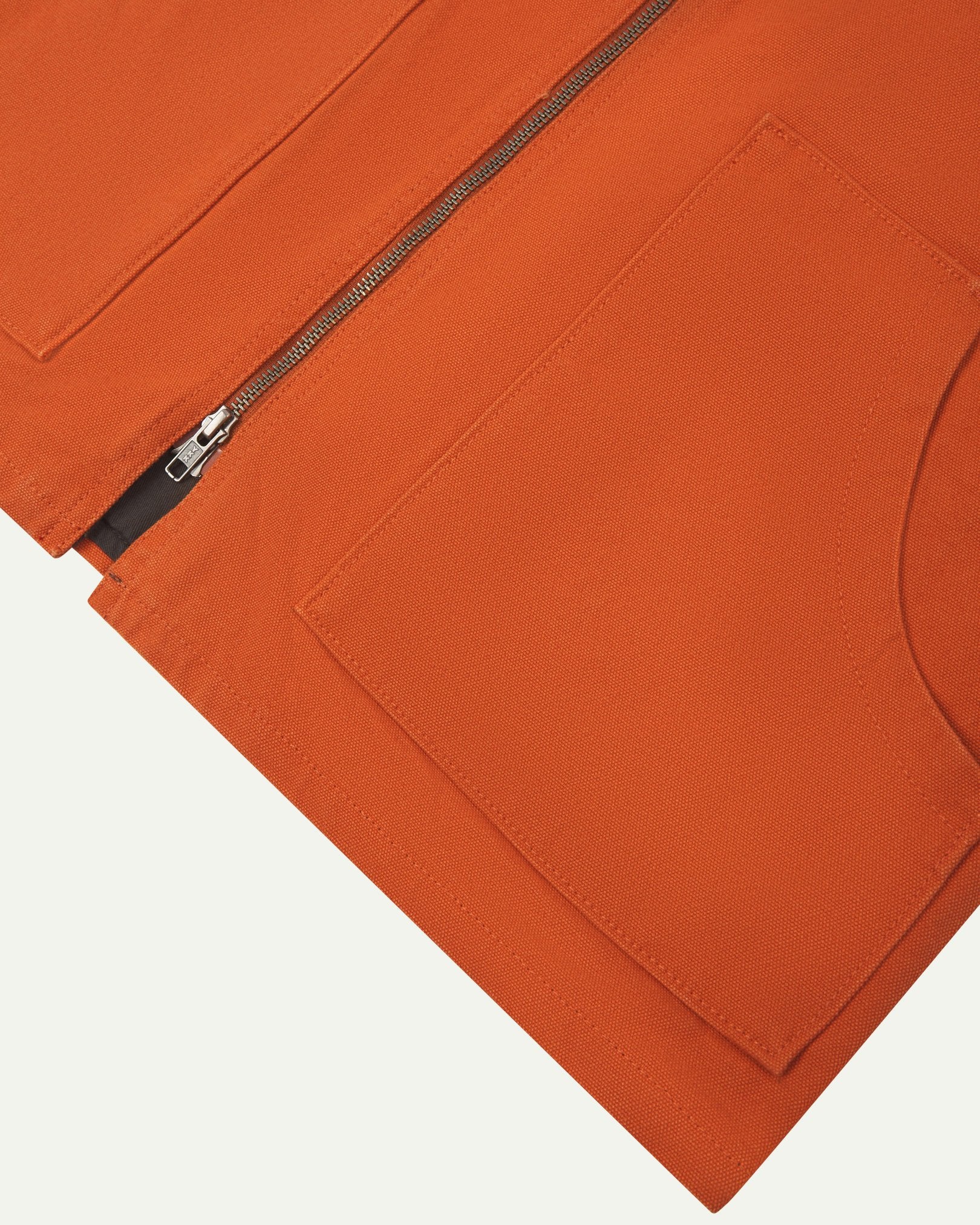 Front flat close-up shot of Uskees golden-orange zip front vest-waistcoat showing the front cut-away patch pockets and double-ended zip.