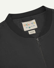 front close up shot of uskees dark grey gilet-style zip front waistcoat showing the front zip, collar and inner brand label at neck