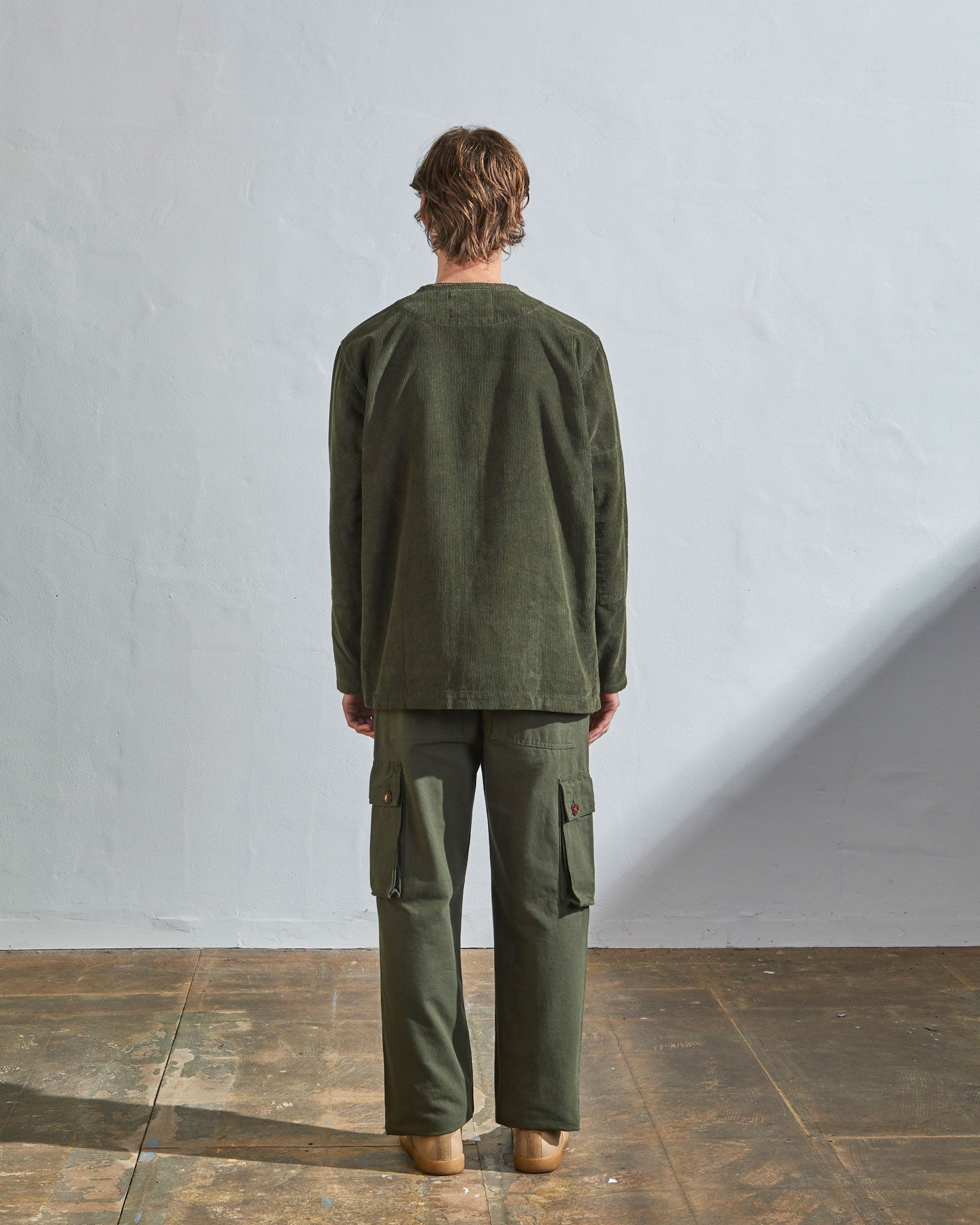 Full-length back view model wearing #5030 Uskees 'vine green' collarless corduroy jacket, emphasising boxy, contemporary silhouette.