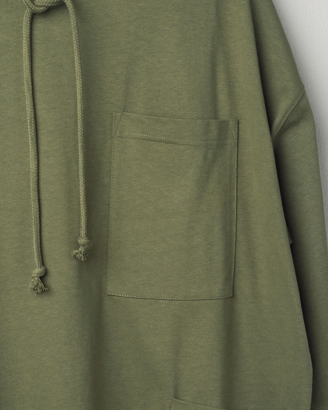 Close-up, top-right view of #3032 army green smock from Uskees showing large breast pocket and adjustable drawstring.