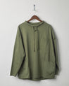 Front view of army green organic cotton #3032 jersey tie neck smock by Uskees, presented on hanger against white background. 