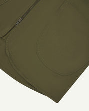 Close-up bottom-half view of #3036 moss-green organic cotton-drill vest with focus on curved pocket detail.