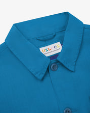 Neck view of Uskees 3040 opal-blue herringbone cotton engineer jacket with focus on collar, Uskees brand label and matching corozo buttons.