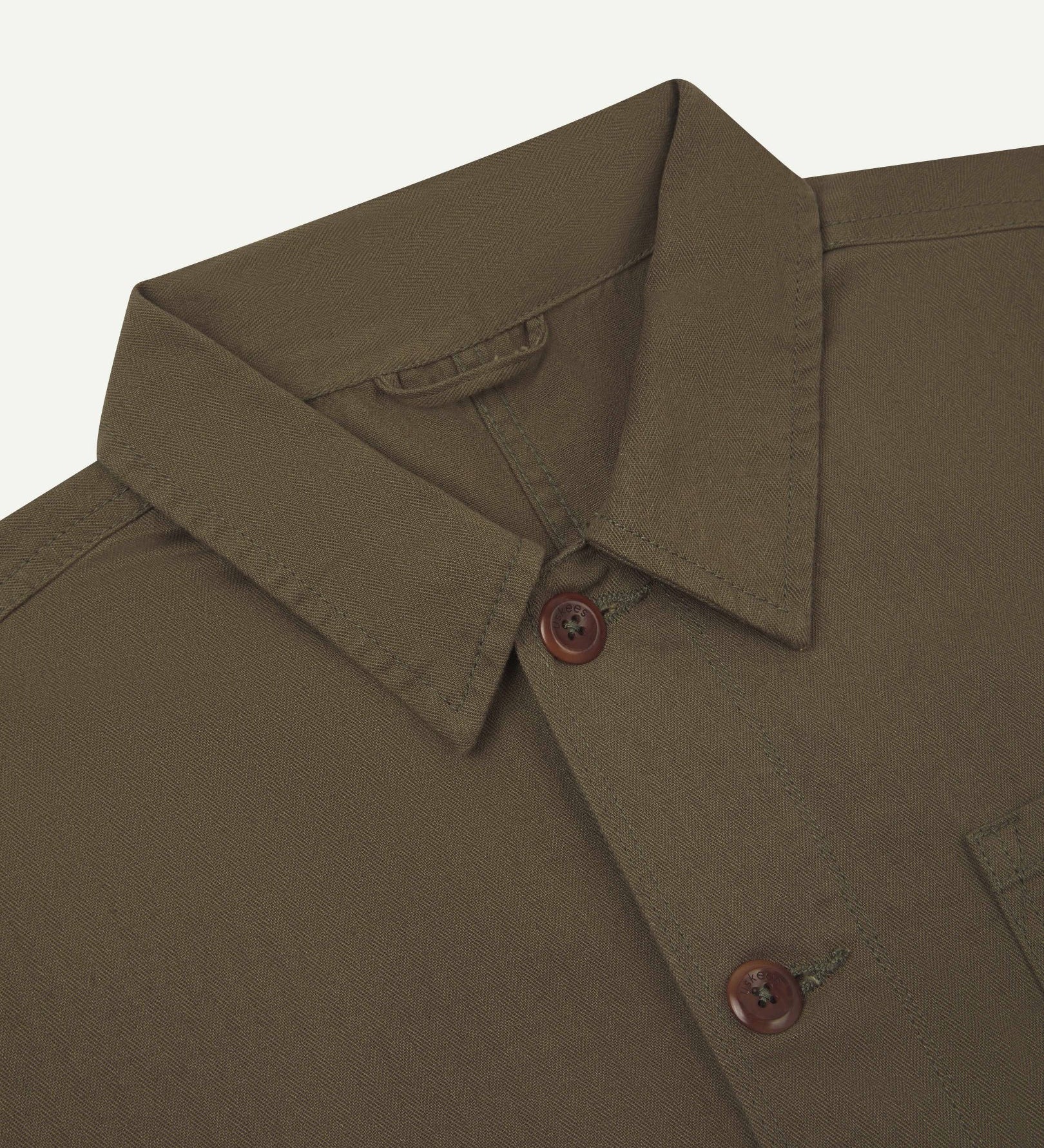 Neck view of Uskees 3040 dark taupe herringbone cotton engineer jacket with focus on collar and matching corozo buttons.