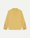 Full back view of Uskees sandstone-yellow organic herringbone cotton engineer jacket showing reinforced elbows and simple lines.