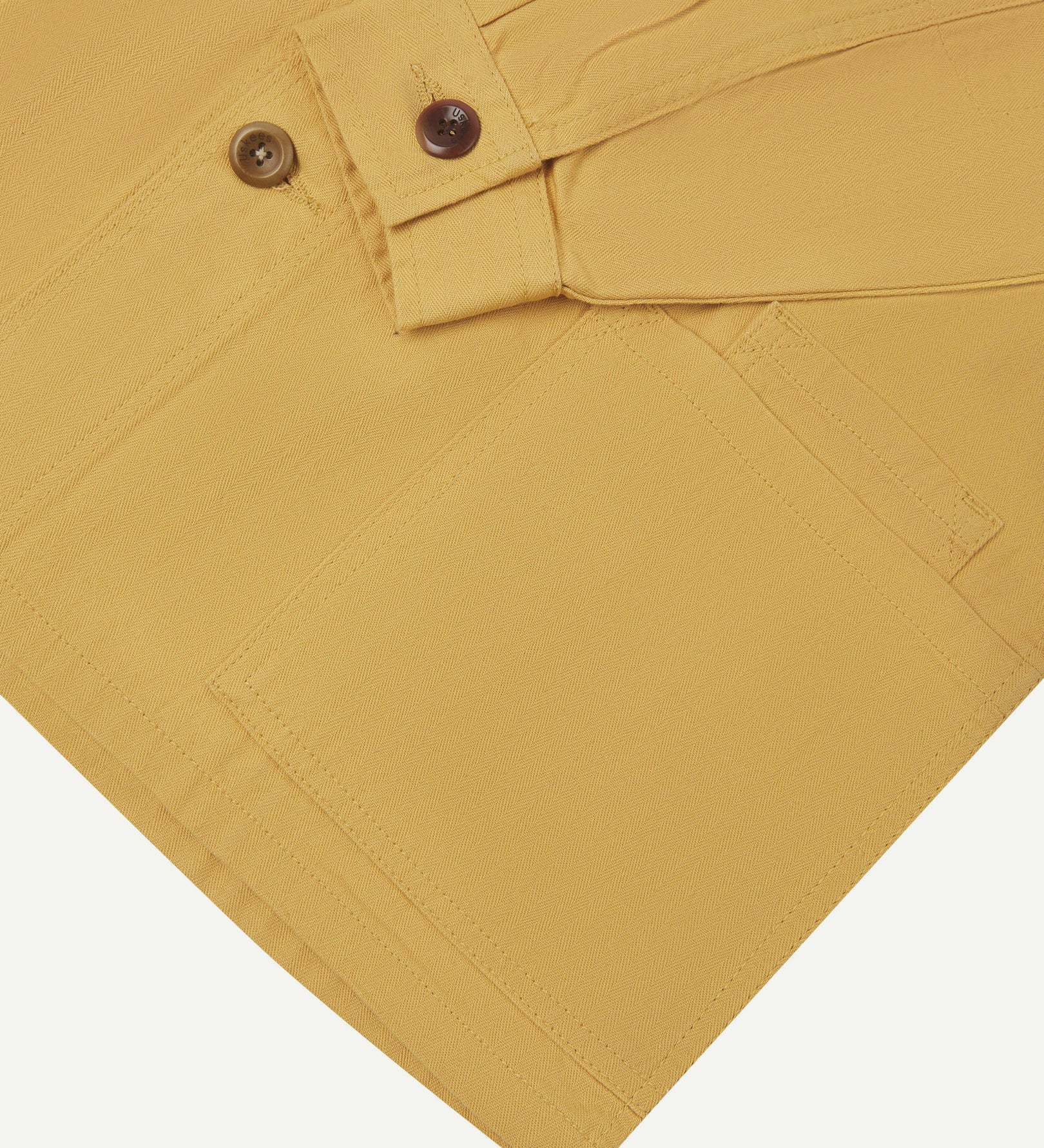 Sleeve view of Uskees 3040 sandstone-yellow herringbone cotton engineer jacket with focus on placket, buttoned cuff and ticket pocket.