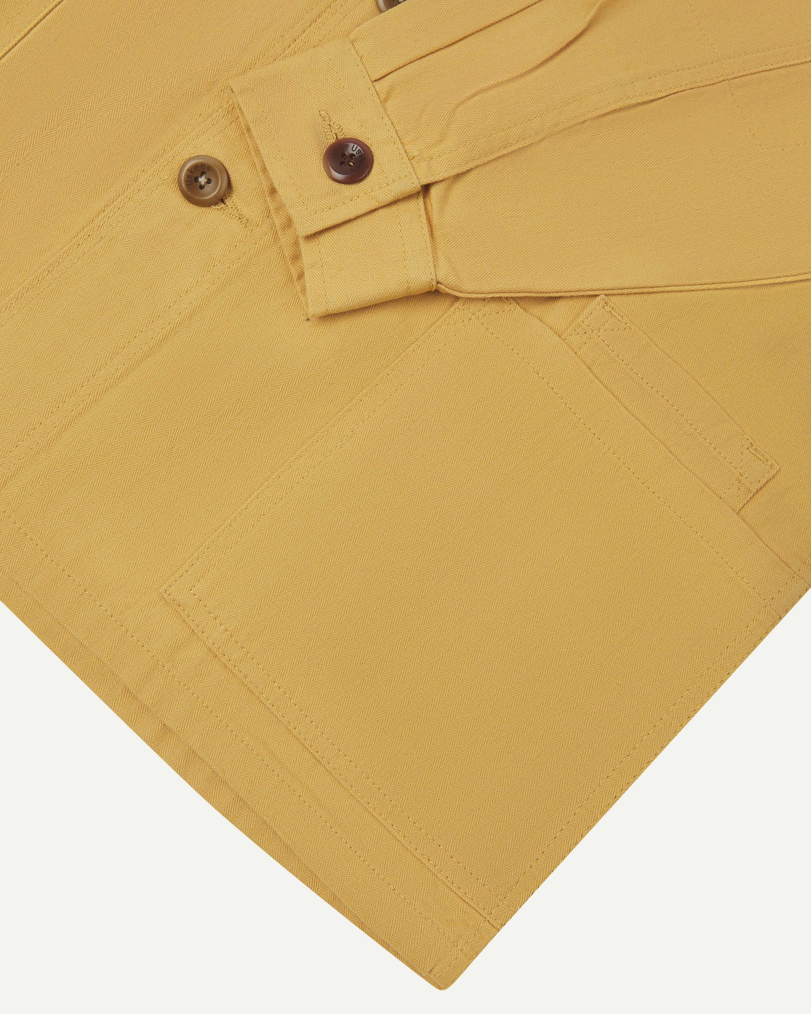 Sleeve view of Uskees 3040 sandstone-yellow herringbone cotton engineer jacket with focus on placket, buttoned cuff and ticket pocket.