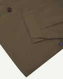 Close-up view of one of two hip pockets, cuff and Uskees branding tag of the 3041 signal jacket. Also is a closer view of the herringbone texture of the dark taupe cotton. 