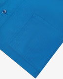 Bottom-right view of one of two hip pockets, hem andcorozo buttons of the 3041 signal jacket. Also is a closer view of the herringbone texture of the opal-blue cotton. 