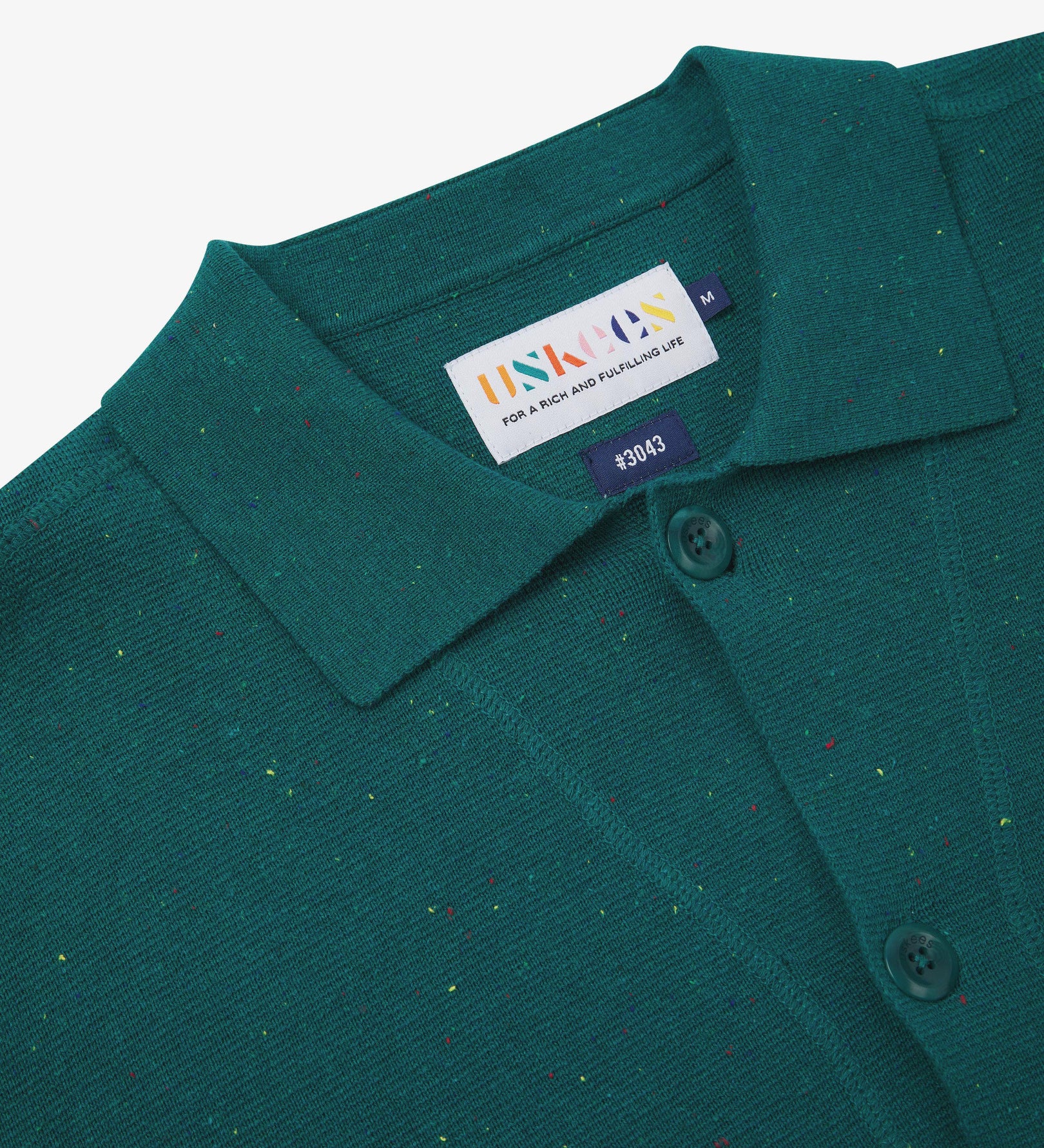 Close-up front view of knitted organic cotton foam green cardigan showing the collar, corozo buttons and Uskees branding label.