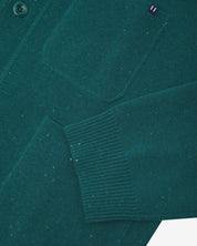 Close-up view of ribbed cuff and pockets of the knitted organic cotton, foam green cardigan. Discreet Uskees branding label visible on chest pocket.