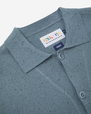 Close-up front view of knitted organic cotton blue-grey cardigan showing the collar, corozo buttons and Uskees branding label.