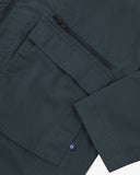 Close up view of Uskees blueberry ripstop field jacket with focus on a zip and gusseted chest pocket, cuff and small branding tab.