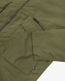 Close up view of Uskees ivy green ripstop field jacket with focus on a zip and gusseted chest pocket , cuff and small branding tab.
