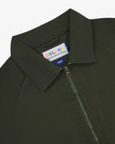 Close up shot of Uskees dark green men's field  jacket showing the brand label on the collar against a white background