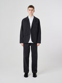 Front view of male model wearing the Uskees 3047 Docklands black blazer unbuttoned, paired with matching Uskees pants.