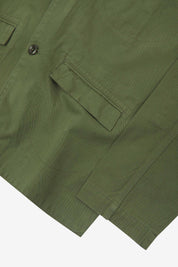 Close-up view of the cuff, jetted hip pocket and corozo buttons of the 3047 docklands blazer from Uskees. Also is a closer view of the texture of the coriander-green organic cotton twill. 