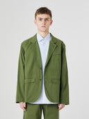 Three-quarter pose of man wearing the Uskees 3047 Docklands coriander green blazer, paired with blue shirt.