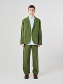 Front view of male model wearing the Uskees 3047 Docklands coriander green blazer unbuttoned, paired with matching Uskees pants.