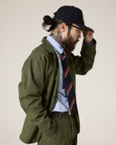 Side view of male model wearing the Uskees green docklands jacket, pale blue shirt and striped tie.