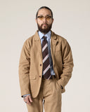 Front view model shot of Uskees khaki docklands blazer worn with a blue shirt and striped Repp tie.