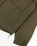 Close up view of Uskees army green Evo shell coat with focus on cuff, waist toggle and welt pocket.