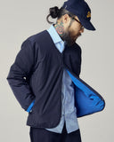 Side view of model wearing Uskees midnight blue Evo liner jacket paired with Uskees shirt and cap.