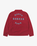 Back view flat shot of Uskees clay red coach jacket for men with focus on the the North Born Uskees slogan, straight-cut hem and elasticated cuffs.