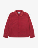 Front flat shot of Uskees clay red coach jacket for men showing sharp, contemporary detailing including slanted welt pockets, cinch hem and popper fastening.