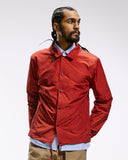 Top-half front view modelling Uskees 3052 clay red blue coach jacket.