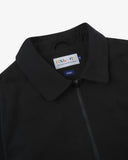 Close up shot of an Uskees zip up bomber jacket for men in black showing the brand label and zip detail.