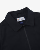 Close up shot of an Uskees zip up bomber jacket for men in dark blue showing the front zipper and brand label at neck.