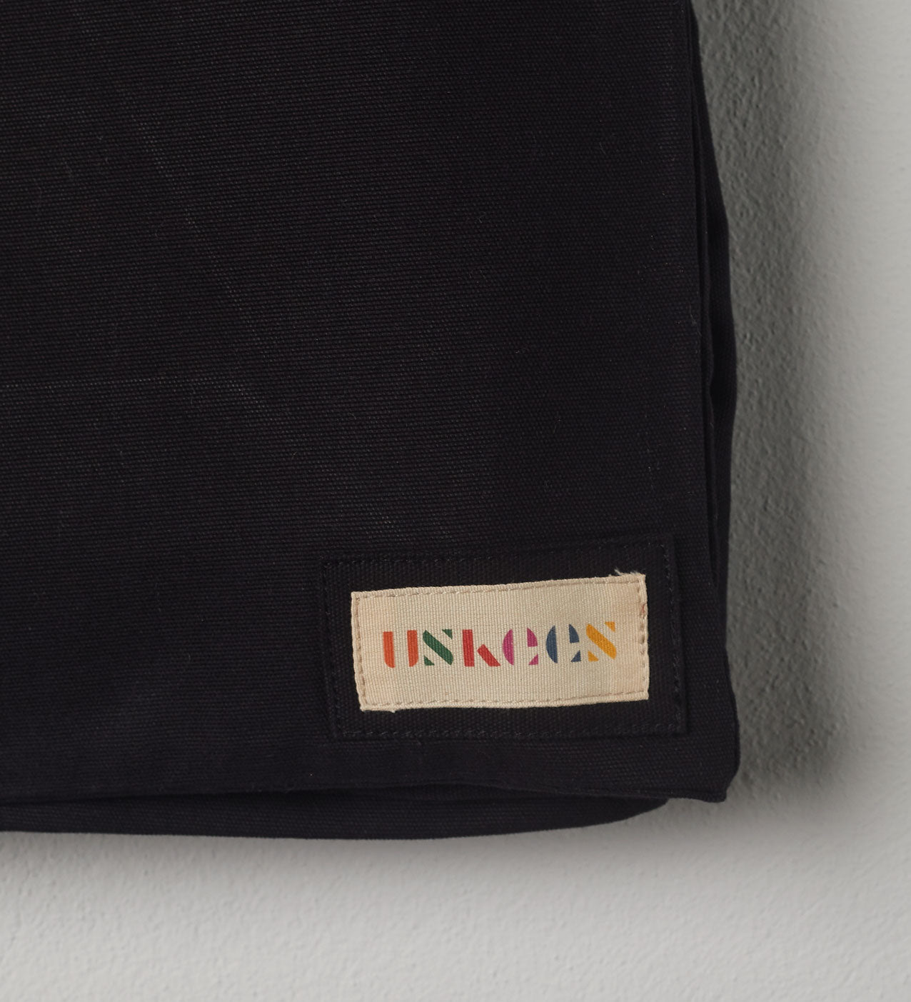Close-up view of Uskees #4001 large tote bag in black showing the Uskees woven label.