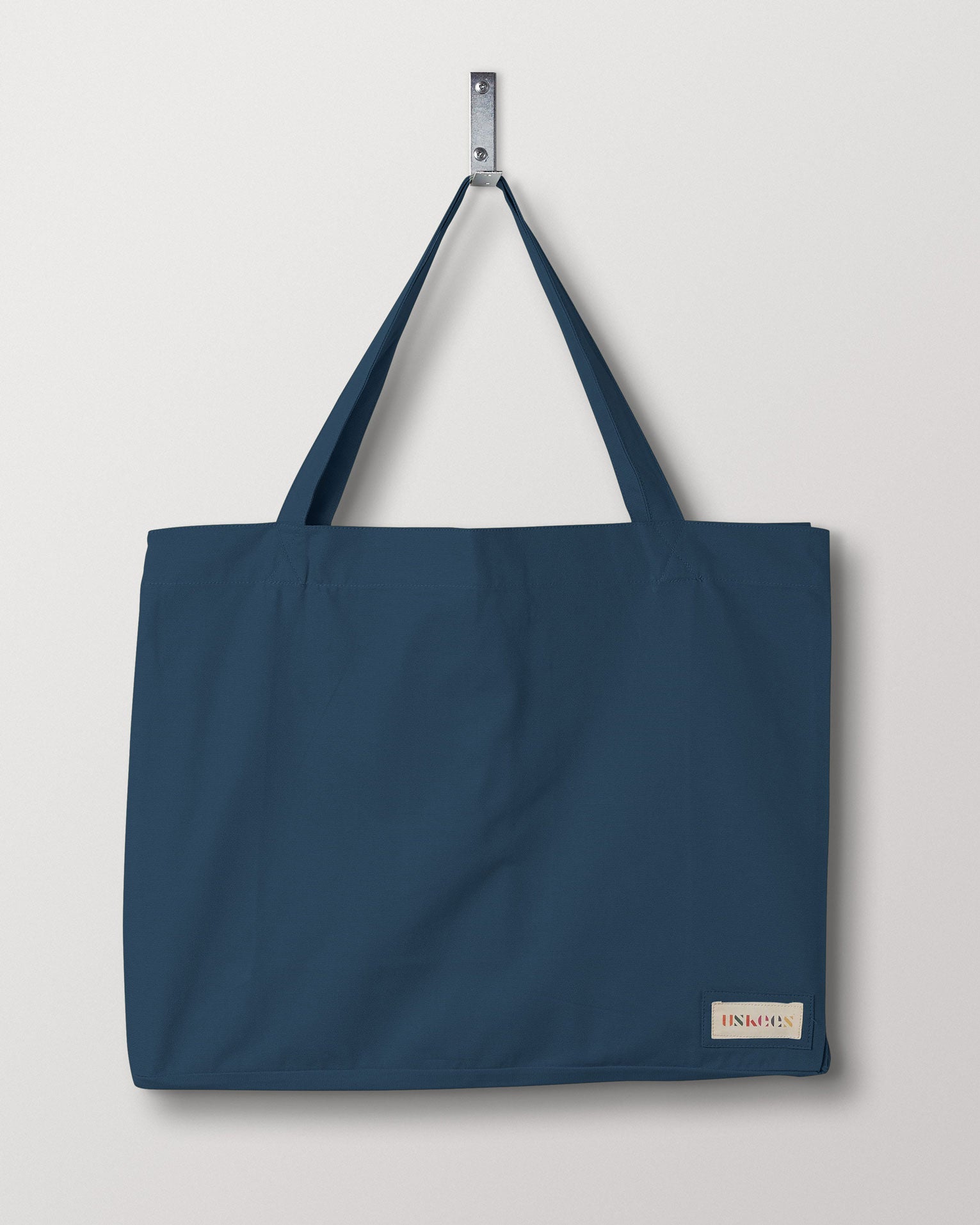 Full front hanging shot of Uskees #4001 large blue tote bag, showing double handles and Uskees woven logo.
