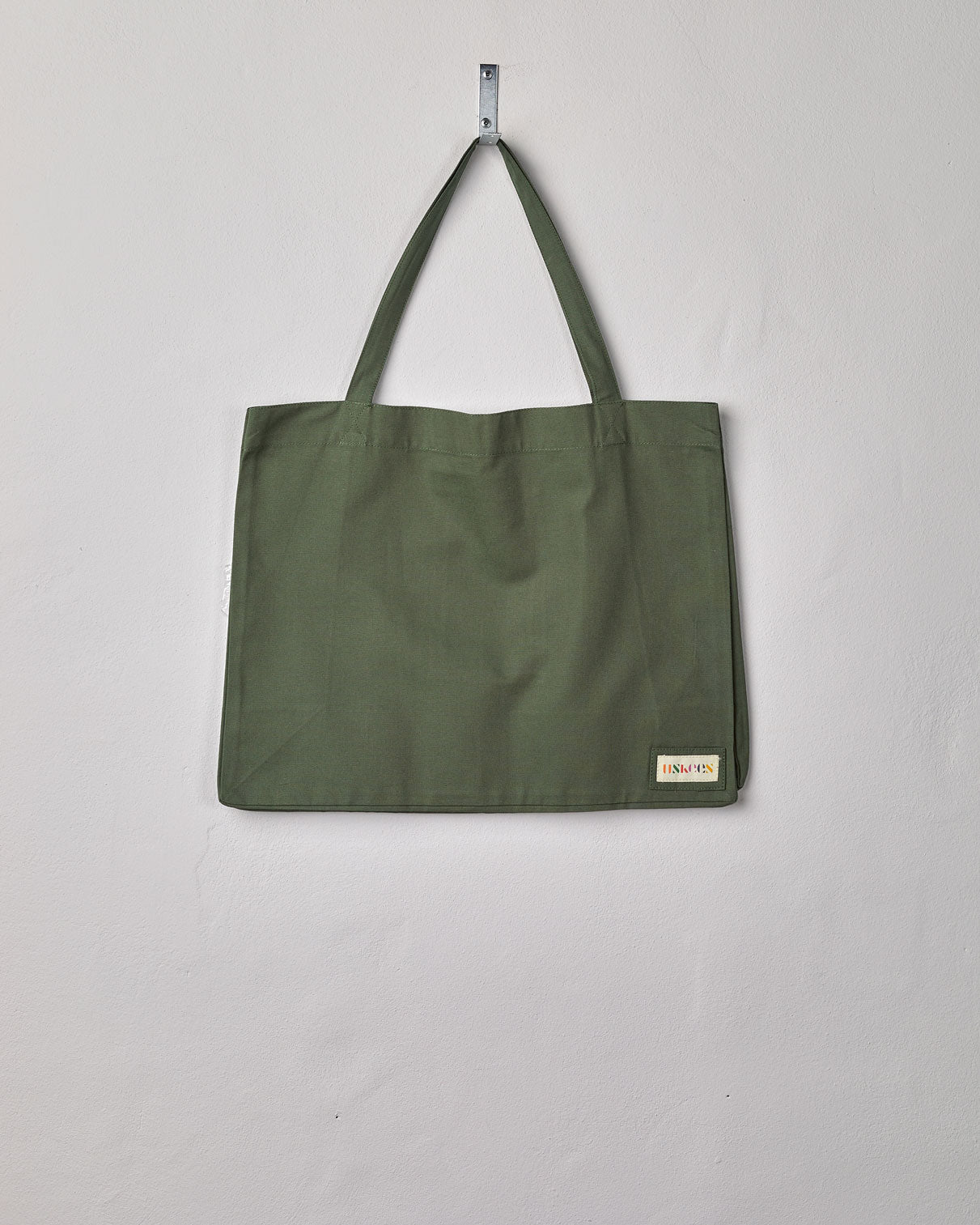 Full front hanging shot of Uskees #4001 large coriander-green tote bag, showing double handles and Uskees woven logo.