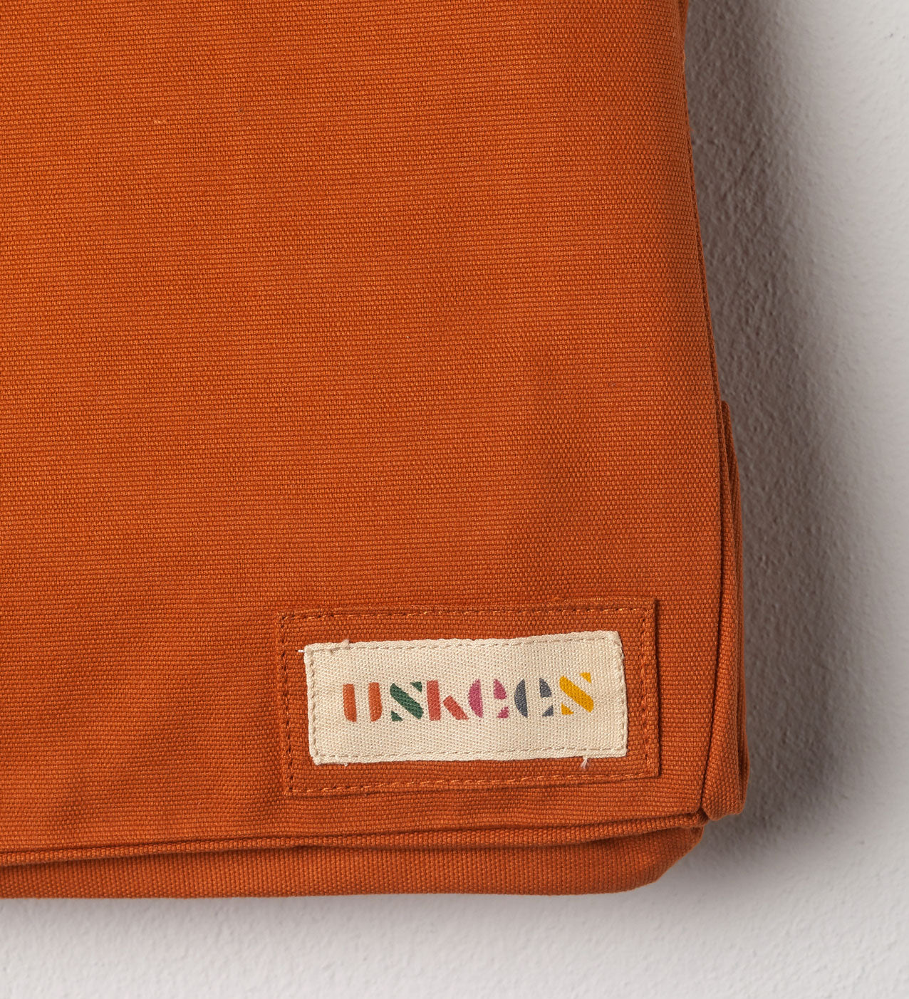 Close-up view of Uskees #4001 large tote bag in orange gold showing the Uskees woven label.