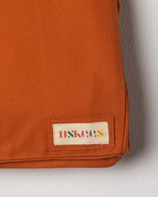 Close-up view of Uskees #4001 large tote bag in orange gold showing the Uskees woven label.