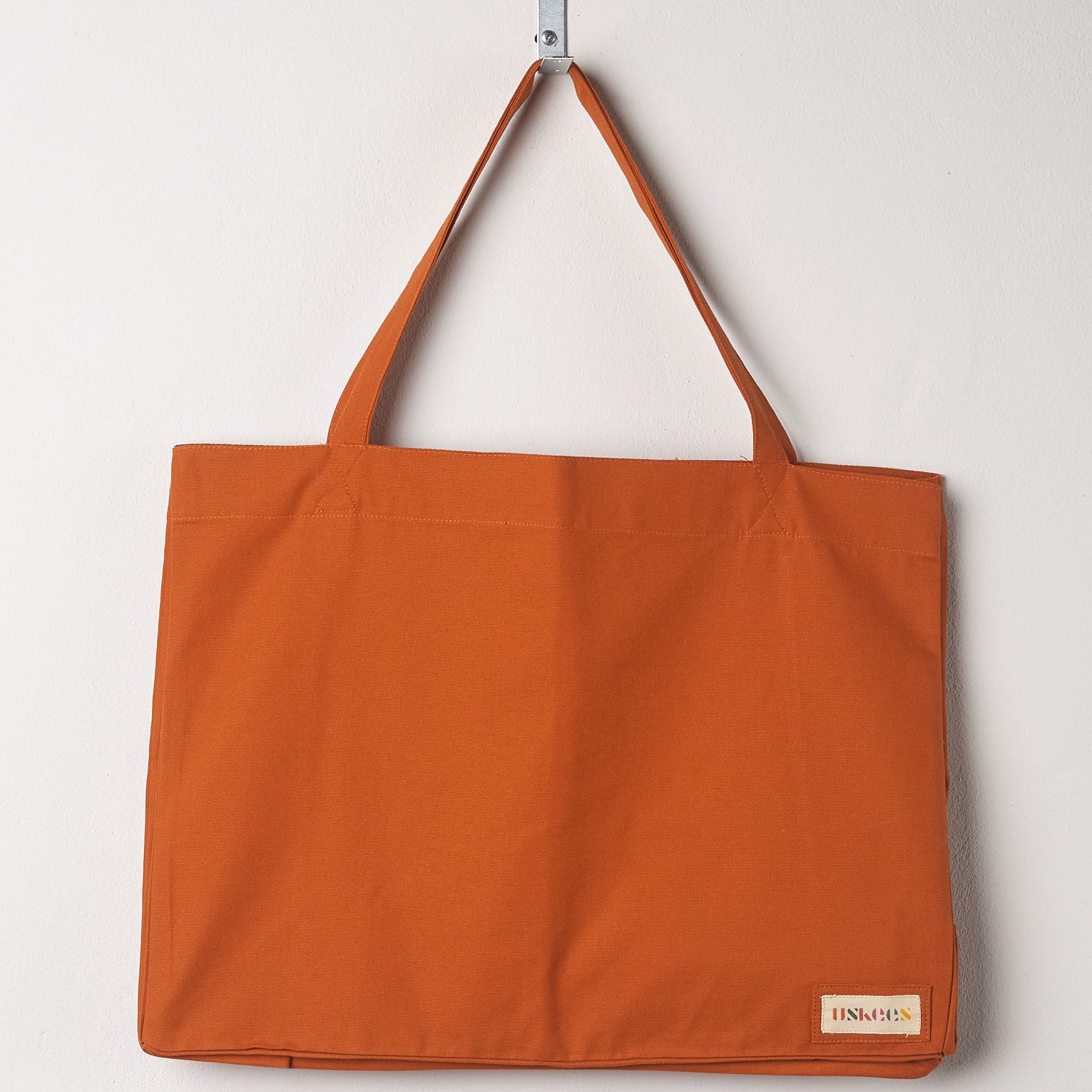 Full front hanging shot of Uskees #4001, large gold tote bag, showing double handles.