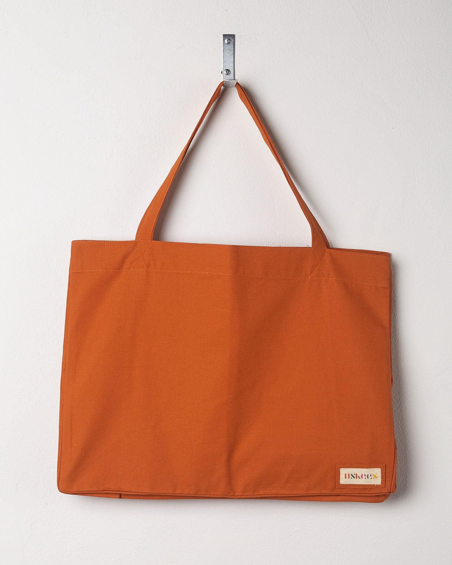 Full front hanging shot of Uskees #4001, large gold tote bag, showing double handles.