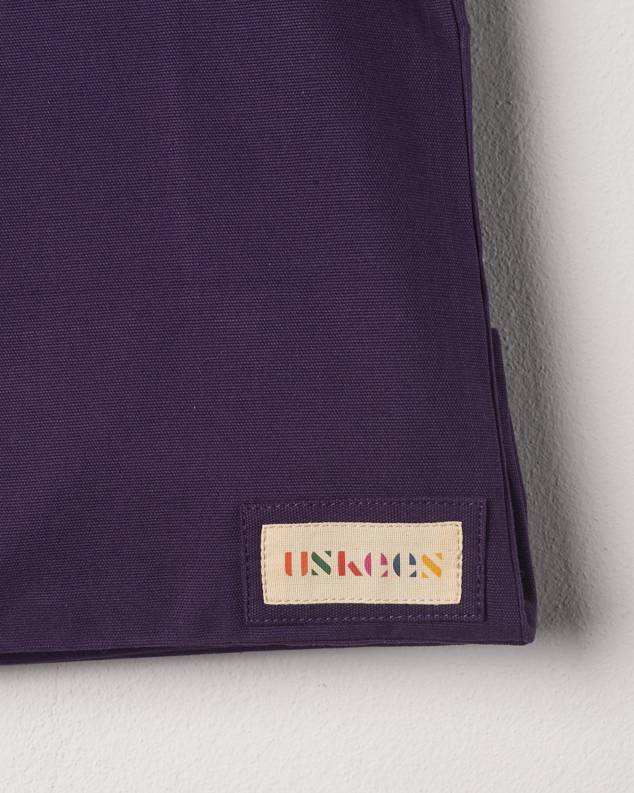 Close-up view of Uskees #4001 large tote bag in purple showing the Uskees woven label.