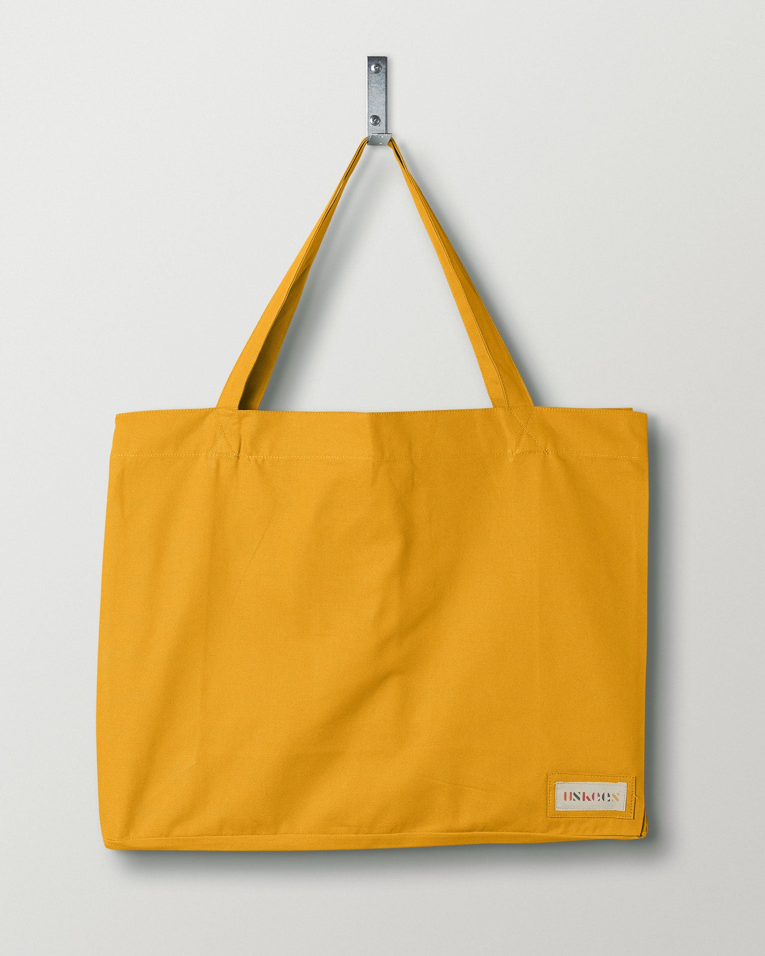 Full, flat view of Uskees #4001, large yellow tote bag, showing twin handles and Uskees woven logo. 