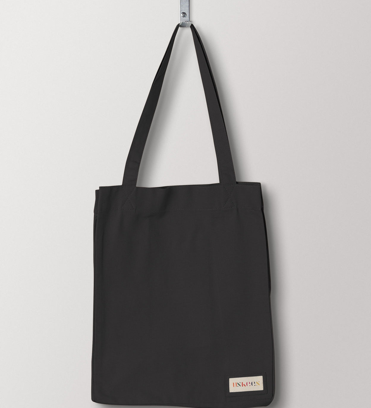 Full front hanging shot of Uskees #4002 small charcoal-grey tote bag, showing double handles and Uskees woven logo.