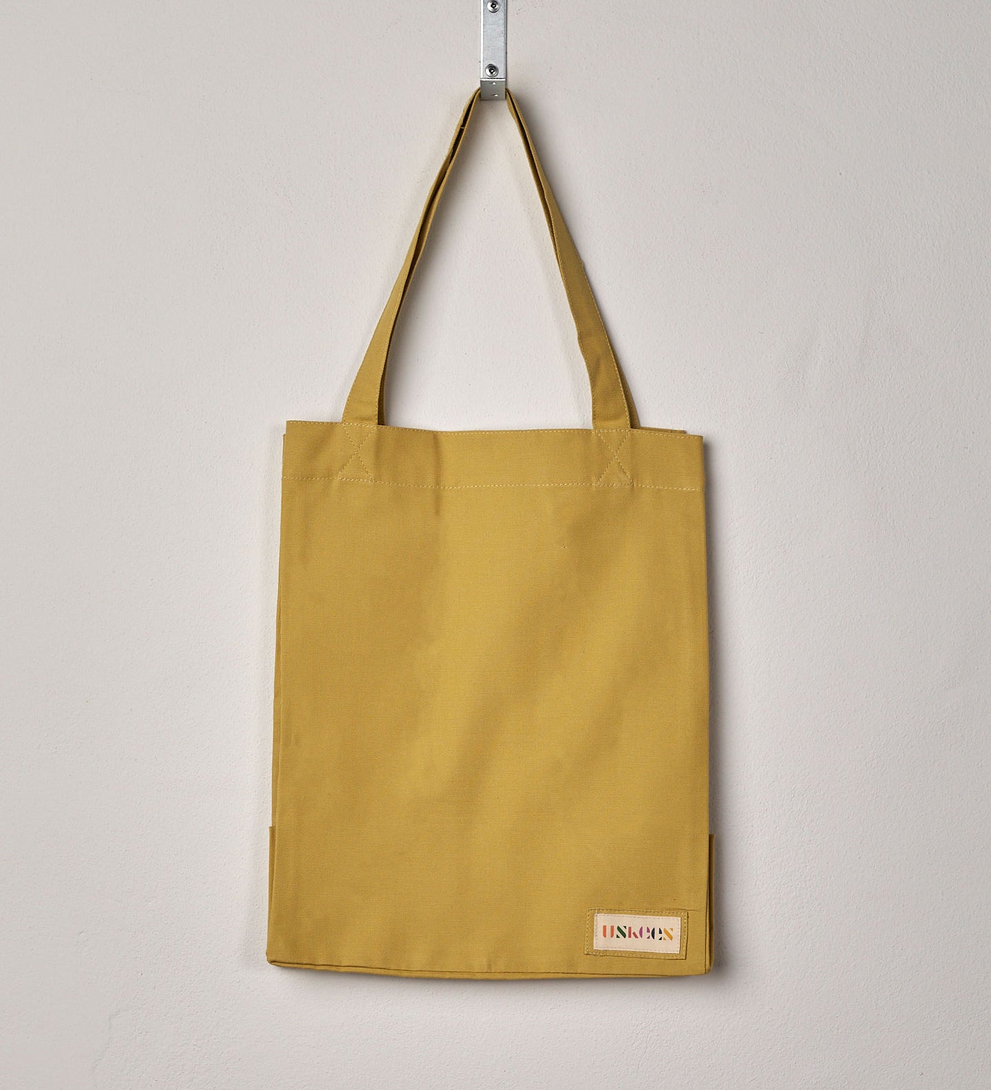 Full front hanging shot of Uskees #4002 small citronella-yellow tote bag, showing double handles and Uskees woven logo.