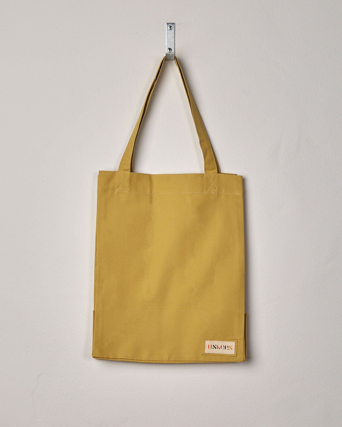 Full front hanging shot of Uskees #4002 small citronella-yellow tote bag, showing double handles and Uskees woven logo.