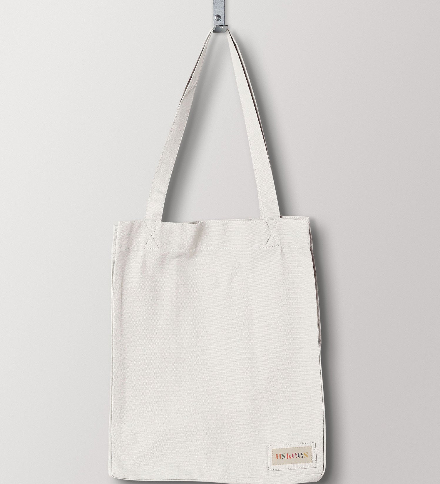 Full front hanging shot of Uskees #4002, small cream tote bag, showing double handles and Uskees woven logo.