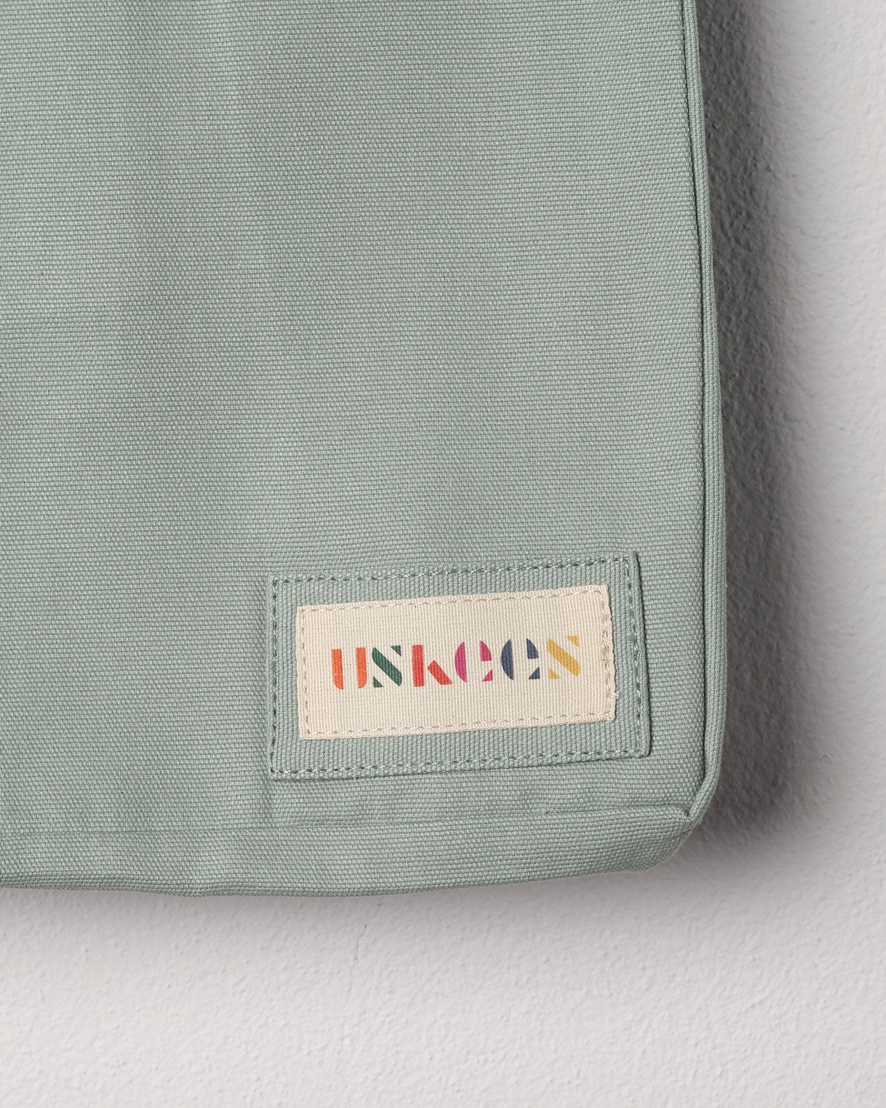Close-up view of Uskees #4002 small tote bag in jade green showing the Uskees woven label.