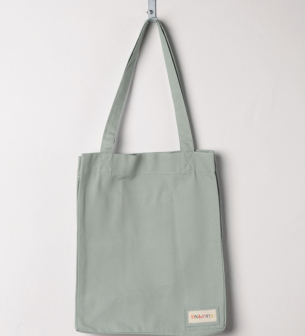Full front hanging shot of Uskees #4002, small jade tote bag, showing double handles and Uskees woven logo.