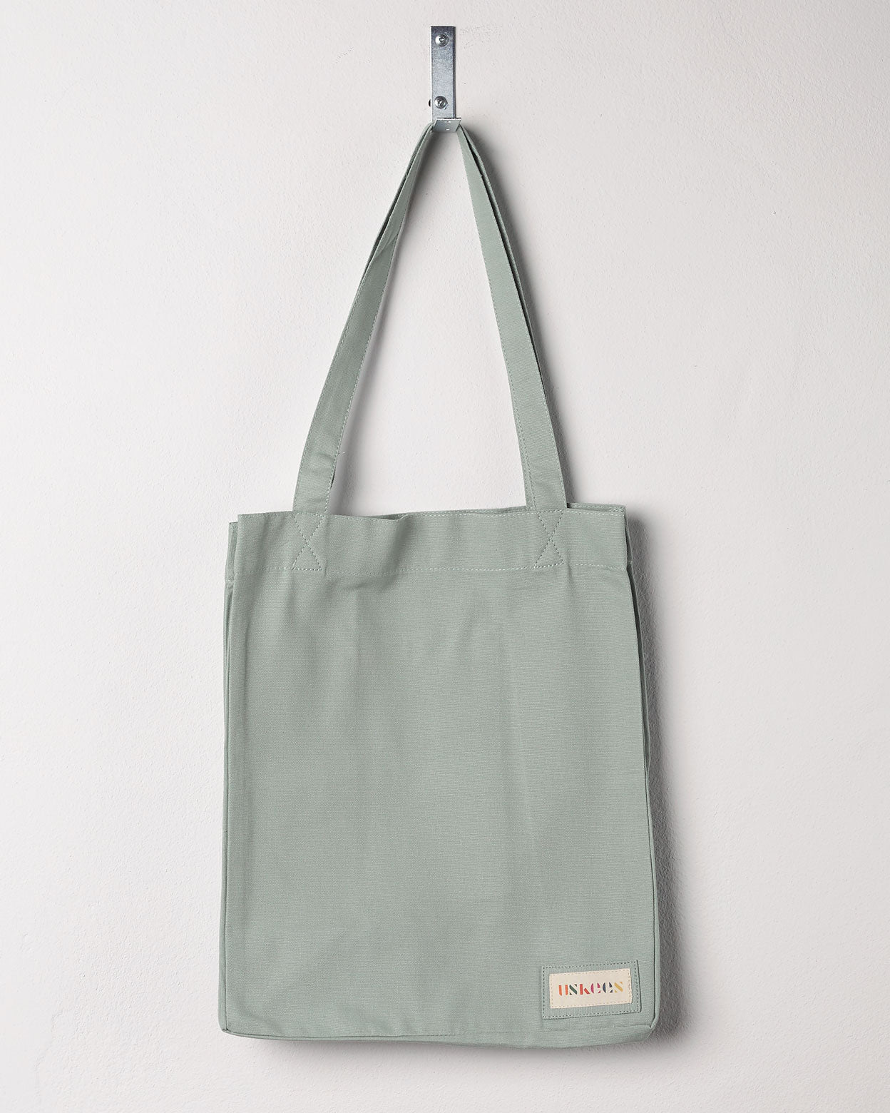 Full front hanging shot of Uskees #4002, small jade tote bag, showing double handles and Uskees woven logo.