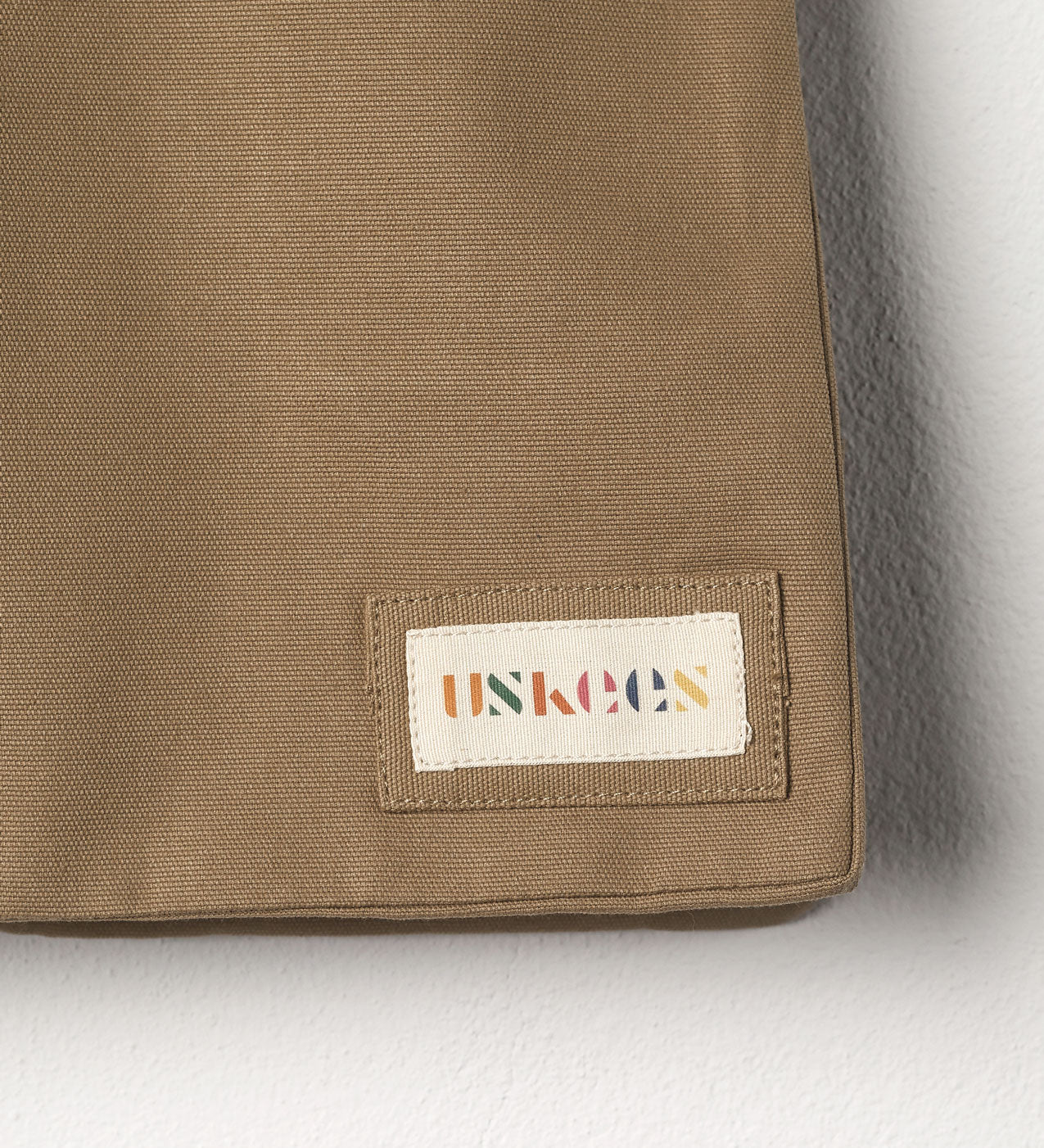 Close-up view of Uskees #4002 small tote bag in khaki showing the Uskees woven label.